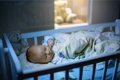 Bebé durmiendo de noche en minicuna