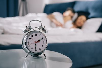 Despertador en el fondo, una pareja durmiendo