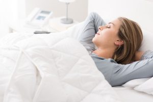 Mujer durmiendo feliz tapada con una manta pesada