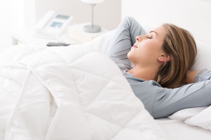 Mujer durmiendo feliz tapada con una manta pesada