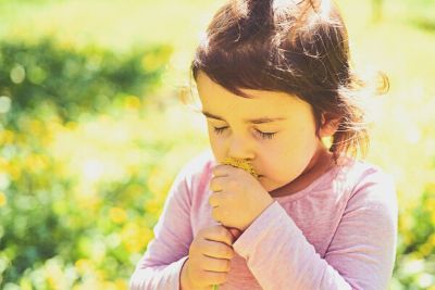 niña oliendo una flor
